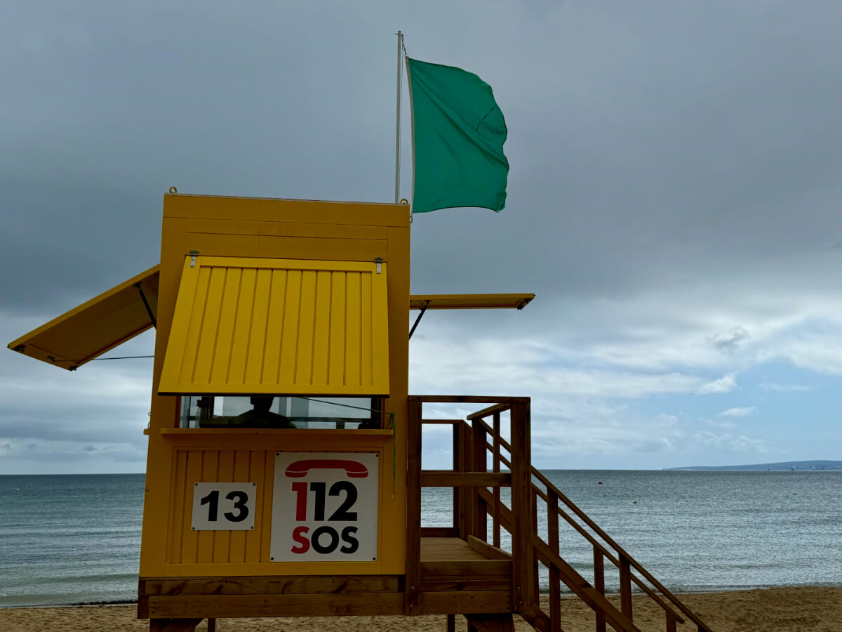 Gelbes Haus der Strandwacht mit grüner Flagge an Mast