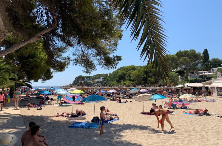 Voller Strand im Sommer auf Mallorca mit blauem Himmel
