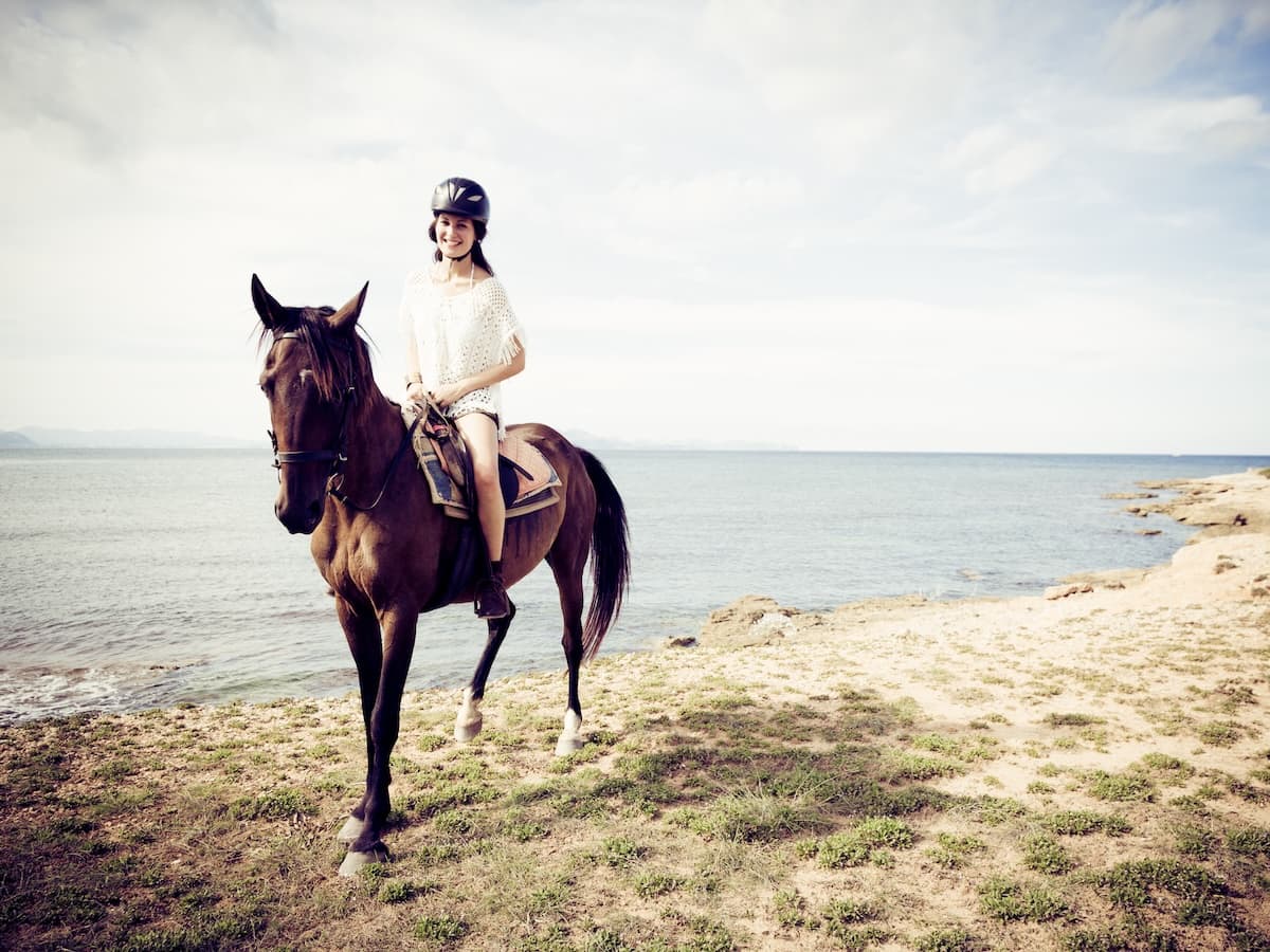 Junge Frau auf einem Pferd an einer Küste von Mallorca