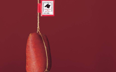 Foto einer aufgehängten Sobrasada vor rotem Hintergrund