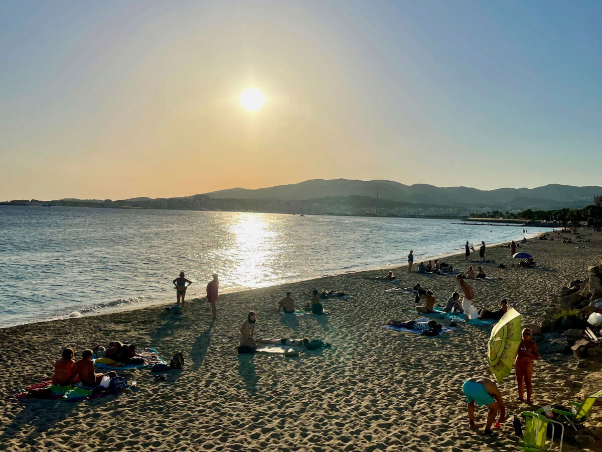 Strand mit Besuchern im September auf Mallorca bei Sonnenuntergang